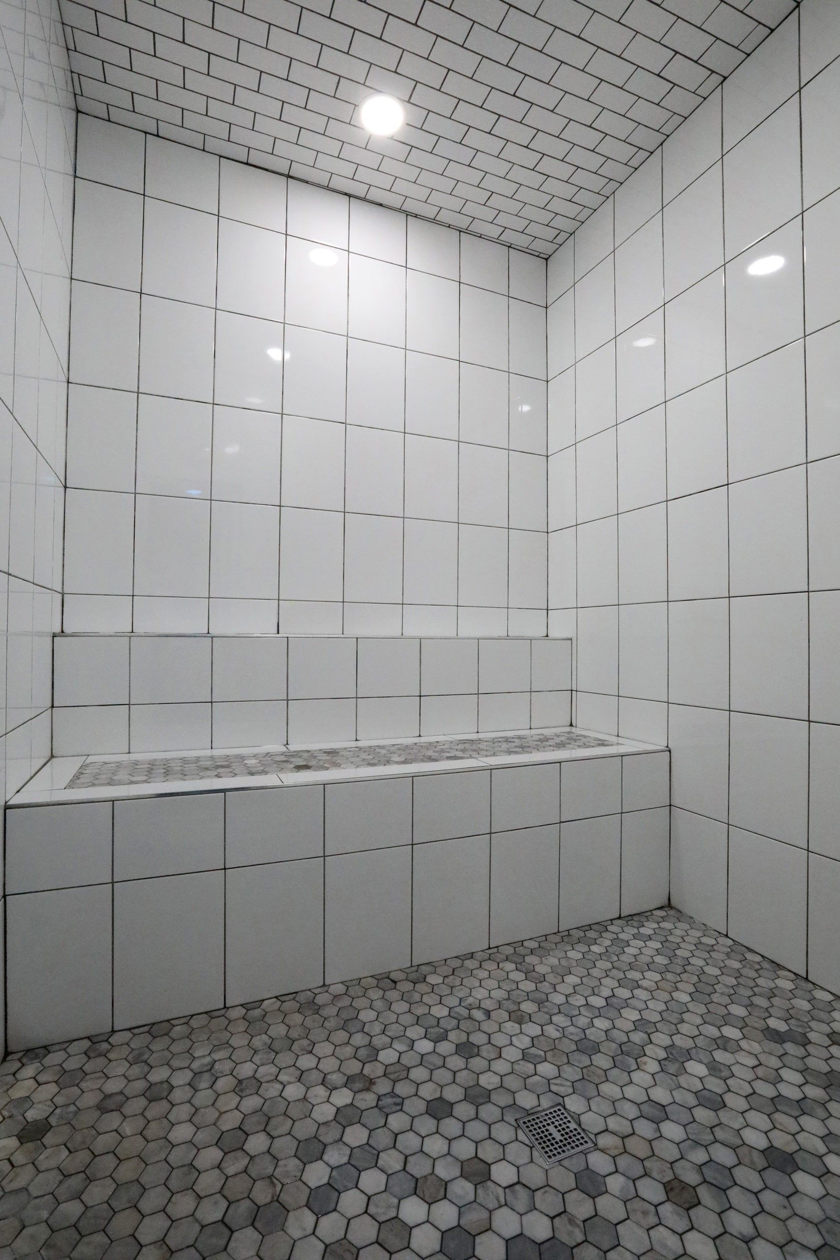 White-tiled steam room with a built-in bench